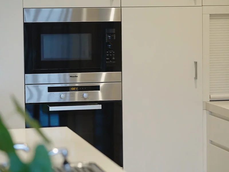 Built-in wall oven and microwave installed within white kitchen cabinetry at Balmoral Street, Waitara