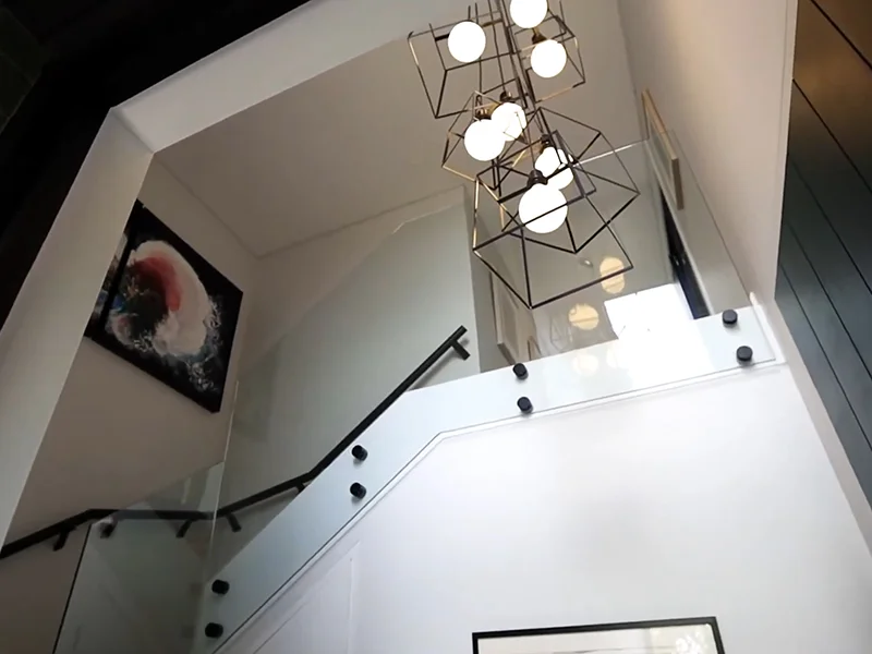 Modern geometric chandelier installed above staircase with glass balustrade at Alan Street, Cammeray