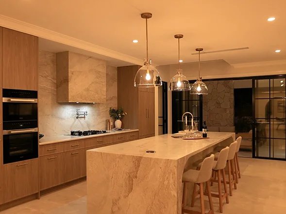 Glass pendant lights installed above marble kitchen island providing warm ambient lighting at Strathfield Avenue, Strathfield