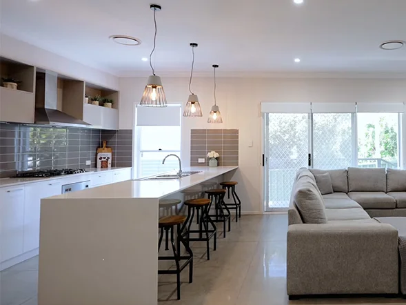 Pendant lights suspended above kitchen island providing warm ambient lighting at Hilary Street, Winston Hills