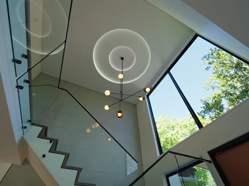 Modern chandelier lighting installation in stair void with large window at The Chase Rd, Turramurra