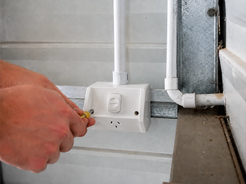 Electrician checking a surface-mounted power point for 10A and 15A outlet suitability in Sydney