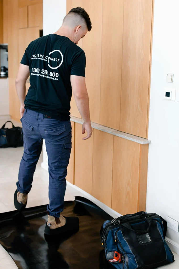 Calibre Connect electrician covering floor and wearing CleanBoot protective boot covers during residential electrical work in Sydney