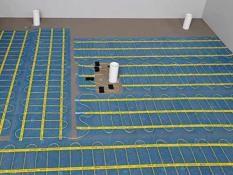 Electric floor heating mats planned around plumbing penetrations before tiling in a Sydney property