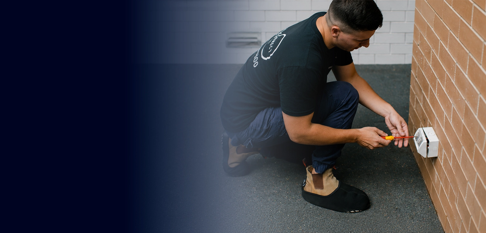 Electrician installing an outdoor power point on a brick wall at a Sydney property