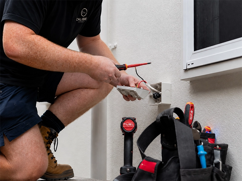 Electrician installing a power point on an exterior wall using a method suited to the wall type in Sydney