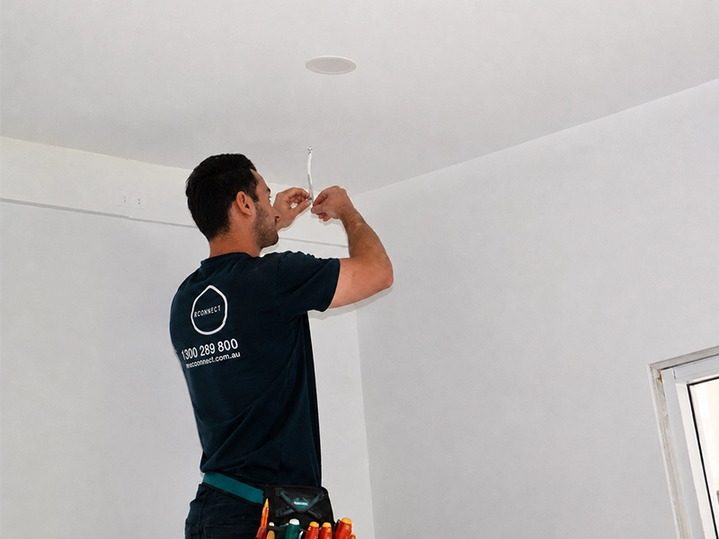 Electrician checking smoke alarm wiring for rental property compliance in Sydney