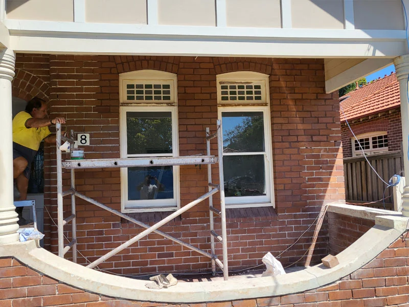 Tuckpointer patching holes in brickwork left by electrical switchboard removal
