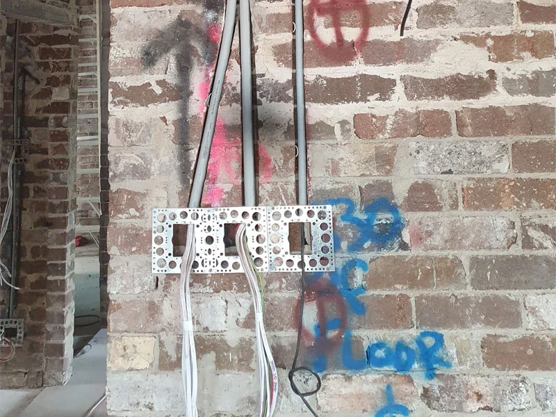Brick wall chasing and electrical rough-in for a Hikvision indoor video intercom room station during a residential renovation.